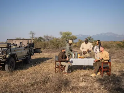 a group of people sitting around a table in a field at Ukanyi Private Luxury Villa in Hoedspruit