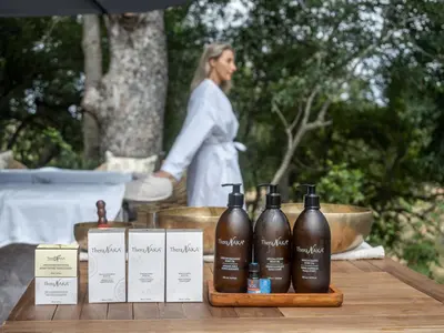 a woman standing behind a table with bottles of wine at Ukanyi Private Luxury Villa in Hoedspruit