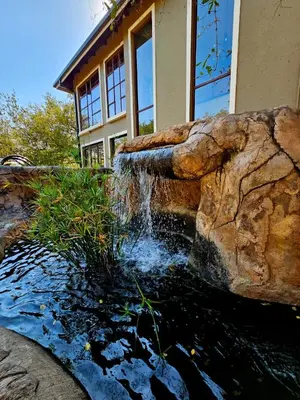 a building with a water fountain in front of a house at The Castello at Kruger in Marloth Park