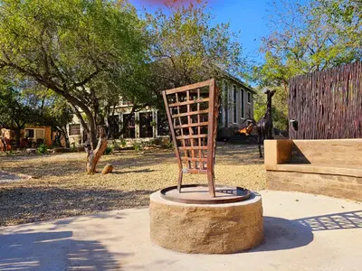 a metal chair sitting on a stump in a park at The Castello at Kruger in Marloth Park