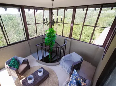 a room with a table and chairs in a room with windows at The Castello at Kruger in Marloth Park
