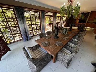 a long wooden table with chairs in a room with windows at The Castello at Kruger in Marloth Park
