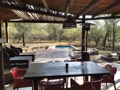 a patio with a table and chairs and a pool at 4609 Ratel in Marloth Park