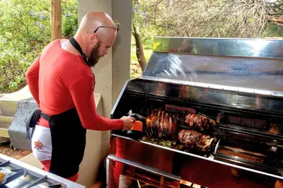a man is cooking food on a grill at The Captain in Pretoria