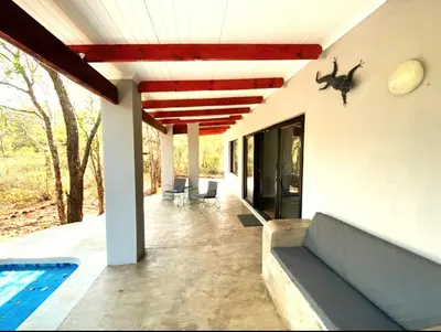 a patio with a couch and a swimming pool at Bushbuck Rest in Marloth Park
