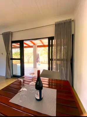 a bottle of wine sitting on a table with glasses at Bushbuck Rest in Marloth Park