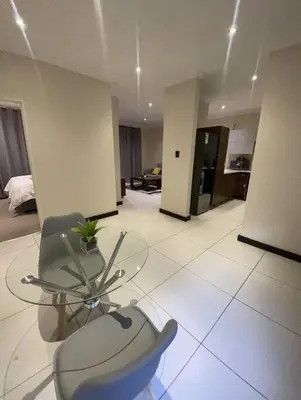 a living room with a glass table and a chair at Priceless Cove. Garden Cottage in Midrand