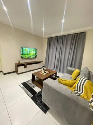 a living room with a couch and a tv at Priceless Cove. Garden Cottage in Midrand