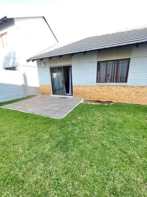 a house with a grass yard in front of it at Priceless Cove. Garden Cottage in Midrand