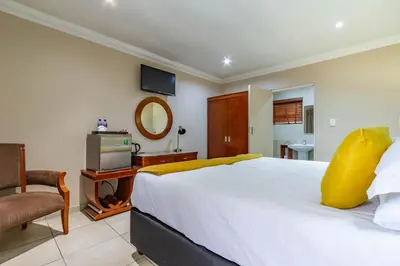 a bedroom with a large white bed and a television at Lakeview Boutique Hotel & Conference Center in Benoni