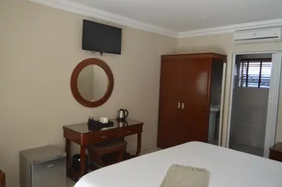 a bedroom with a bed and a dresser and a mirror at Lakeview Boutique Hotel & Conference Center in Benoni