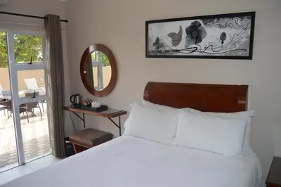 a bedroom with a bed and a mirror and a table at Lakeview Boutique Hotel & Conference Center in Benoni