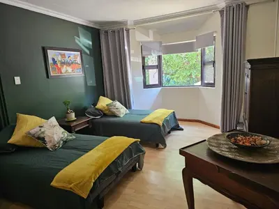 a hotel room with two beds and a table at Giraffe's Rest, Self Catering Studio Apartment in White River
