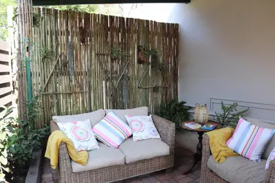 a wicker couch with pillows on a patio at Giraffe's Rest, Self Catering Studio Apartment in White River