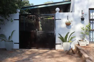 a black door in a white wall with potted plants at Giraffe's Rest, Self Catering Studio Apartment in White River