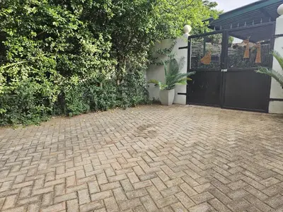 a brick driveway with a black gate and a house at Giraffe's Rest, Self Catering Studio Apartment in White River