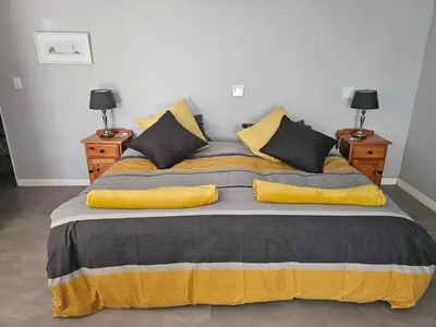 a large bed with yellow and gray blankets and pillows at Giraffe's Rest, Self Catering Studio Apartment in White River