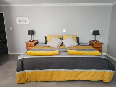 a bedroom with a large bed with yellow pillows at Giraffe's Rest, Self Catering Studio Apartment in White River