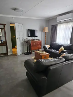 a living room with a couch and a tv at Giraffe's Rest, Self Catering Studio Apartment in White River