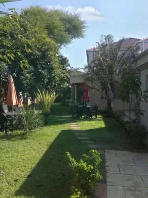 a yard with chairs and tables and a umbrella at Sidze Guest House in Polokwane