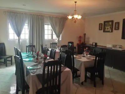 a dining room with a long table and chairs at Sidze Guest House in Polokwane