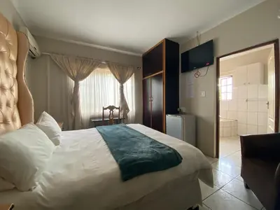 a bedroom with a large white bed and a bathroom at Sidze Guest House in Polokwane