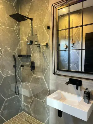 a bathroom with a sink and a shower with a mirror at Swan Lake Suites in Benoni