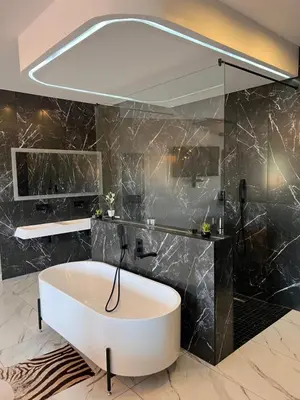 a bathroom with a white tub and a black wall at Swan Lake Suites in Benoni