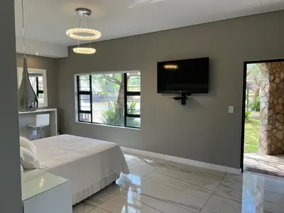 a bedroom with a bed and a flat screen tv at Swan Lake Suites in Benoni