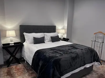 a bedroom with a large bed with two tables and two lamps at Waterkloof Nature Reserve Studio Apartment in Pretoria