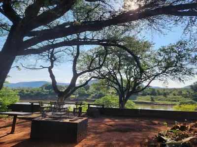 a picnic table with a view of a river at River Cottage Lodge in Malelane