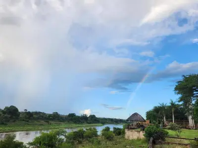 a rainbow in the sky over a river at River Cottage Lodge in Malelane
