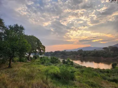 a view of a river with a sunset in the background at River Cottage Lodge in Malelane