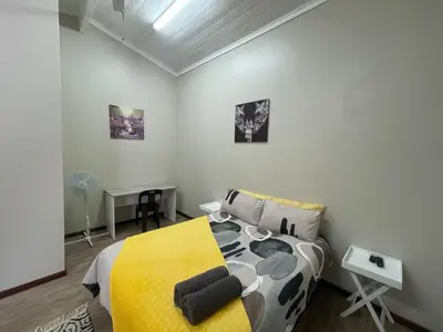 a bedroom with a bed with a yellow blanket at Blue Haven Guesthouse in Polokwane