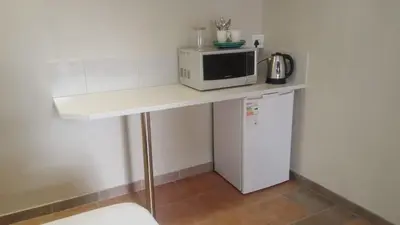 a white counter with a microwave and a refrigerator at Blue Haven Guesthouse in Polokwane