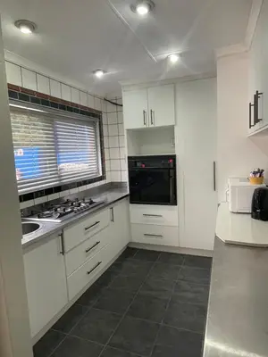 a kitchen with white cabinets and a stove top oven at Blue Haven Guesthouse in Polokwane