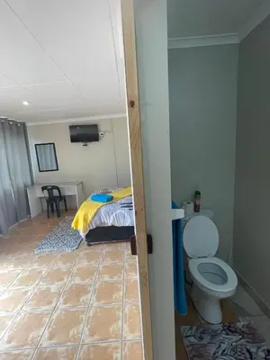a bathroom with a bed and a toilet in a room at Blue Haven Guesthouse in Polokwane