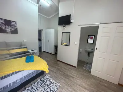 a bedroom with a yellow bed and a television at Blue Haven Guesthouse in Polokwane