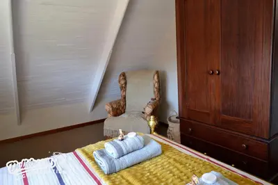 a bedroom with a chair and a bed with two pillows at Critchley Common 24 in Dullstroom
