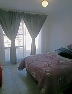 a bedroom with a bed and a window with curtains at eManzini Guesthouse in Matibidi