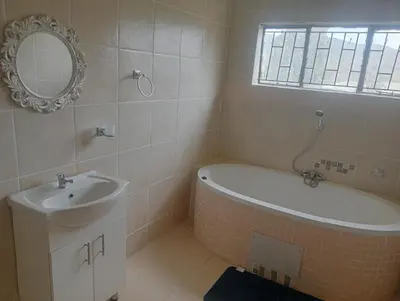 a bathroom with a tub and a sink and a mirror at eManzini Guesthouse in Matibidi