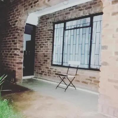 a chair in front of a brick wall with a window at eManzini Guesthouse in Matibidi