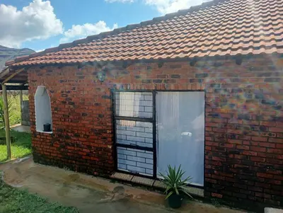 a red brick house with a large window at eManzini Guesthouse in Matibidi
