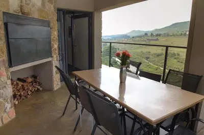 a table and chairs in a room with a fireplace at Walkersons Riverview in Dullstroom