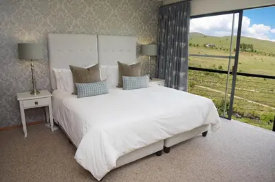 a bedroom with a large white bed with a large window at Walkersons Riverview in Dullstroom
