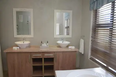 a bathroom with two sinks and two mirrors at Walkersons Riverview in Dullstroom