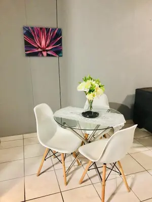 a glass table with white chairs and a vase of flowers at Menlyn Comfort in Pretoria