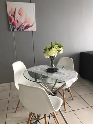 a table with white chairs and a vase of flowers on it at Menlyn Comfort in Pretoria