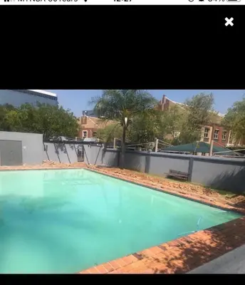 a large blue swimming pool in front of a building at Menlyn Comfort in Pretoria