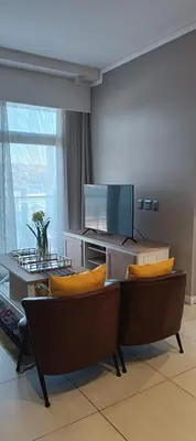 a living room with couches and a flat screen tv at Menlyn Maine Trilogy Apartment 808 in Pretoria